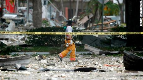 A firefighter walks through the remains of a building after an explosion on Saturday, July 6, 2019, in Plantation, Fla. 
