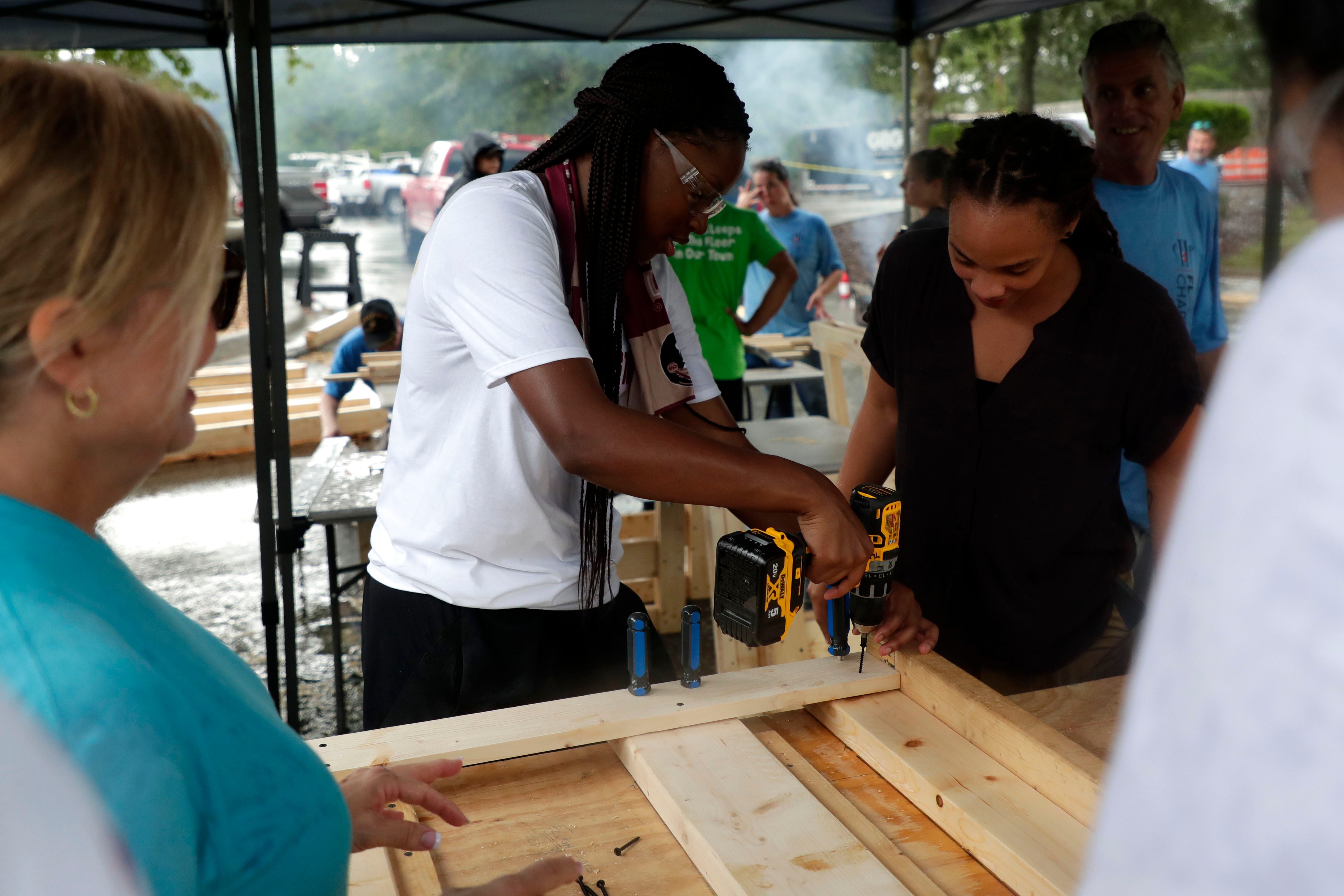 Bianca Jackson, a member of the Florida State women's basketball team, center, drills a screw to piece together a bunk bed for children in the Big Bend. FSU women's basketball teamed up with Texas Roadhouse and other volunteers to complete the project Tuesday, July 23, 2019. 