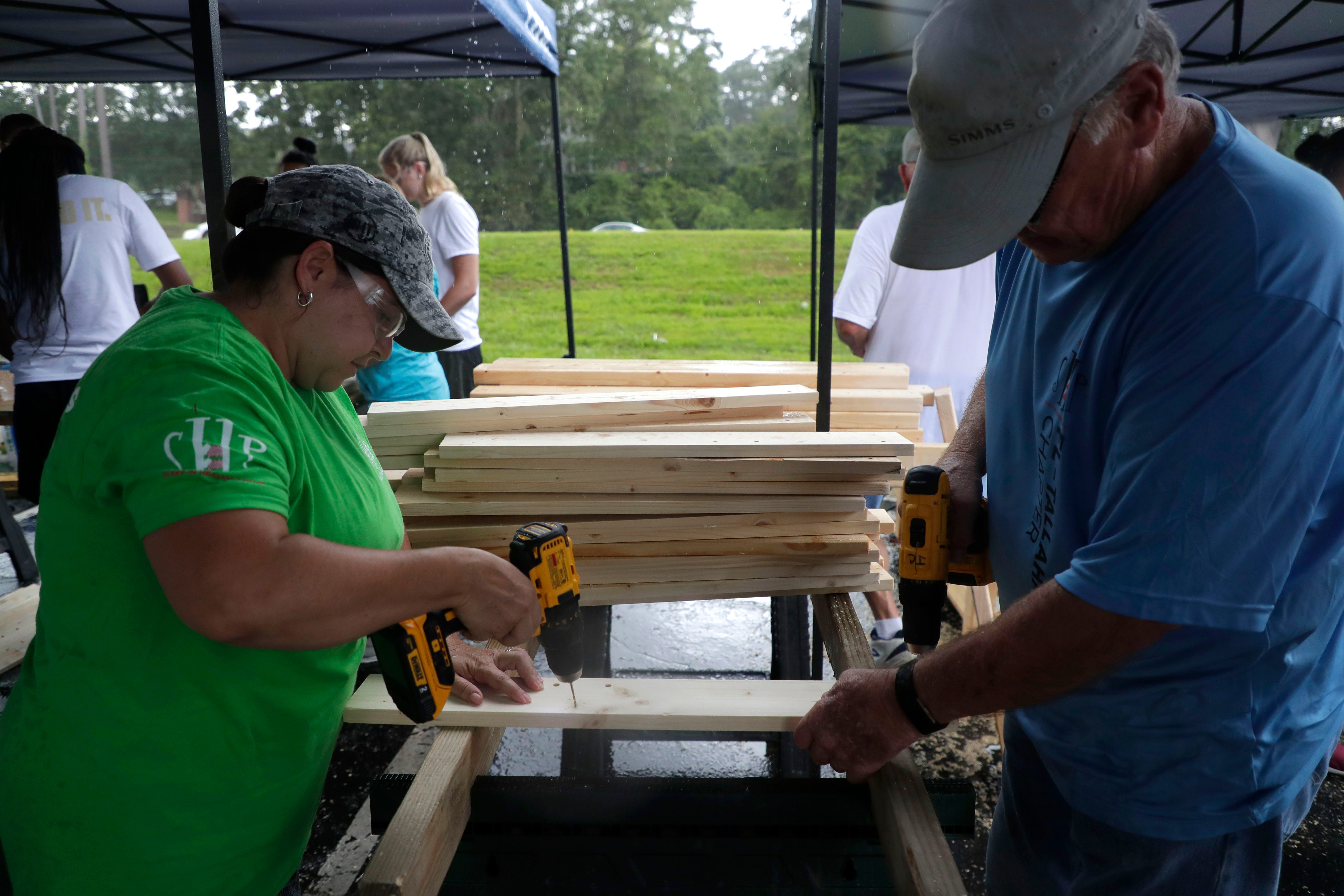 Michelle Clinger, a server at Texas Roadhouse, left, and Dennis Croft, who is retired from the Department of Children and Families, work together to drill holes into a piece of wood. FSU women's basketball teamed up with Texas Roadhouse and other volunteers to build bunkbeds for children in the Big Bend Tuesday, July 23, 2019.