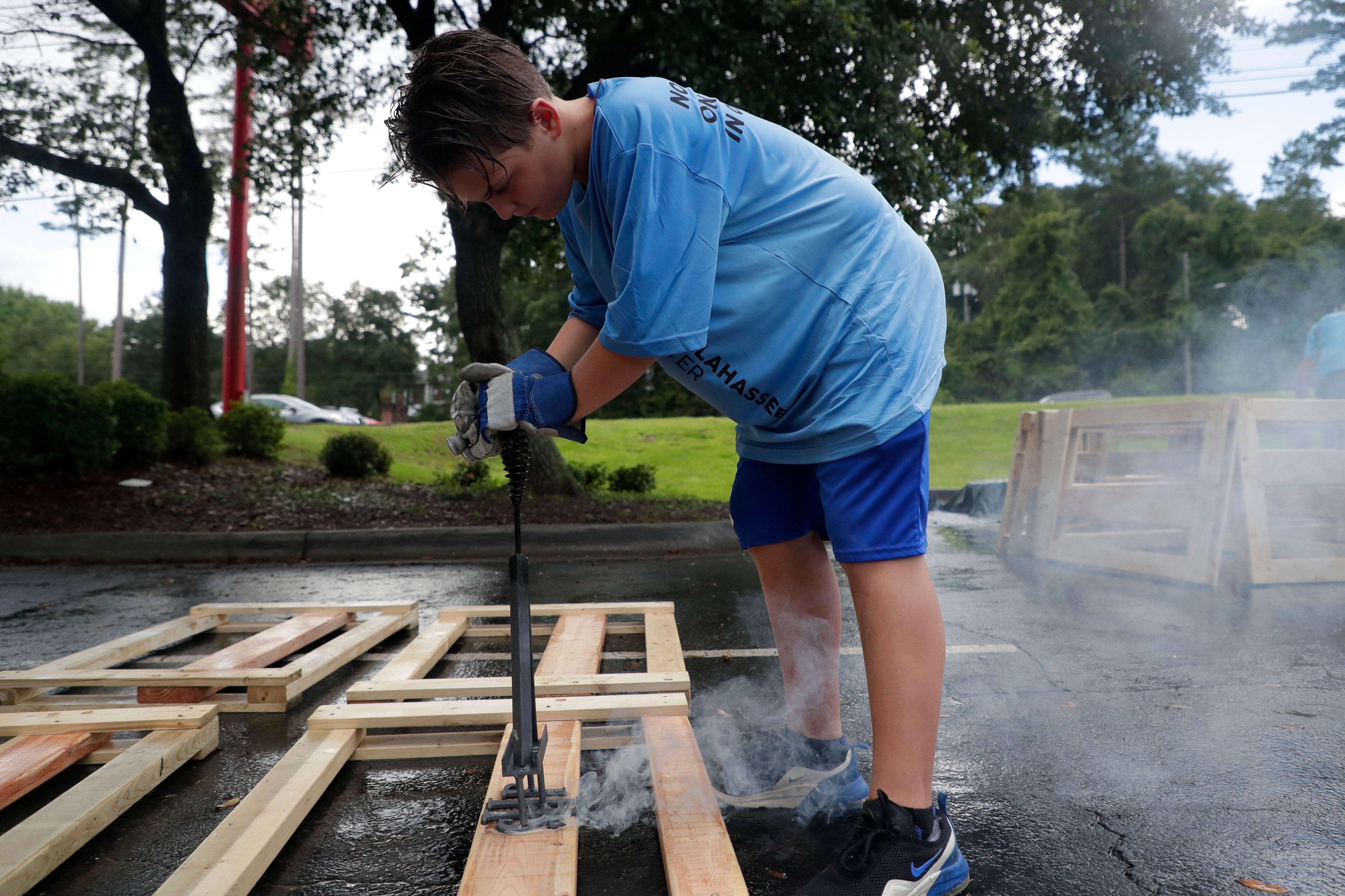 Mason Stafford, 11, brands the Sleep in Heavenly Peace logo to a headboard. FSU women's basketball teamed up with Texas Roadhouse and other volunteers to build bunkbeds for children in the Big Bend Tuesday, July 23, 2019.