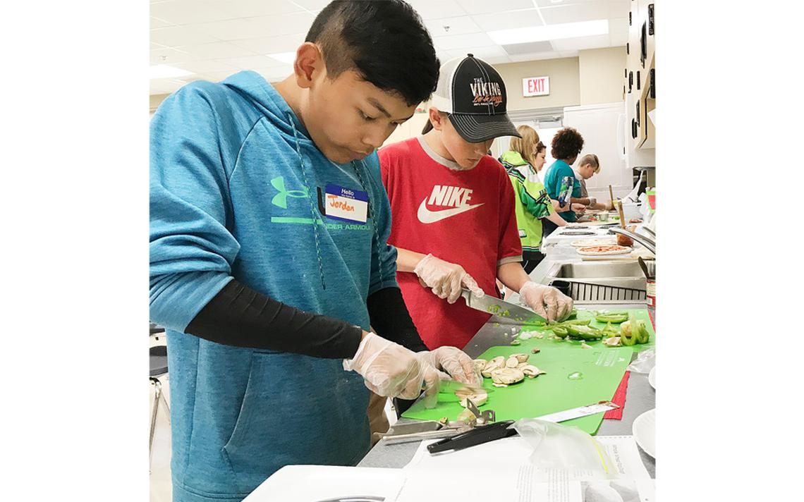 Jordan Boonpa and Sawyer Latvala concentrate on cutting vegetables for their pizzas. Each group of four students had enough pizza dough to make two pizzas during the Cooking Matters class Wednesday, June 26. Jamie Lund/Pine Journal