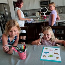 Nora Watts, 6, and her sister, Eve, 4, pick out pens before doing some educational worksheets with their sister, Reese, 9, top right, and mother, Amy, top left, to prepare for the coming school year at their home in Lehi, Utah, on Saturday, Aug. 17, 2019.