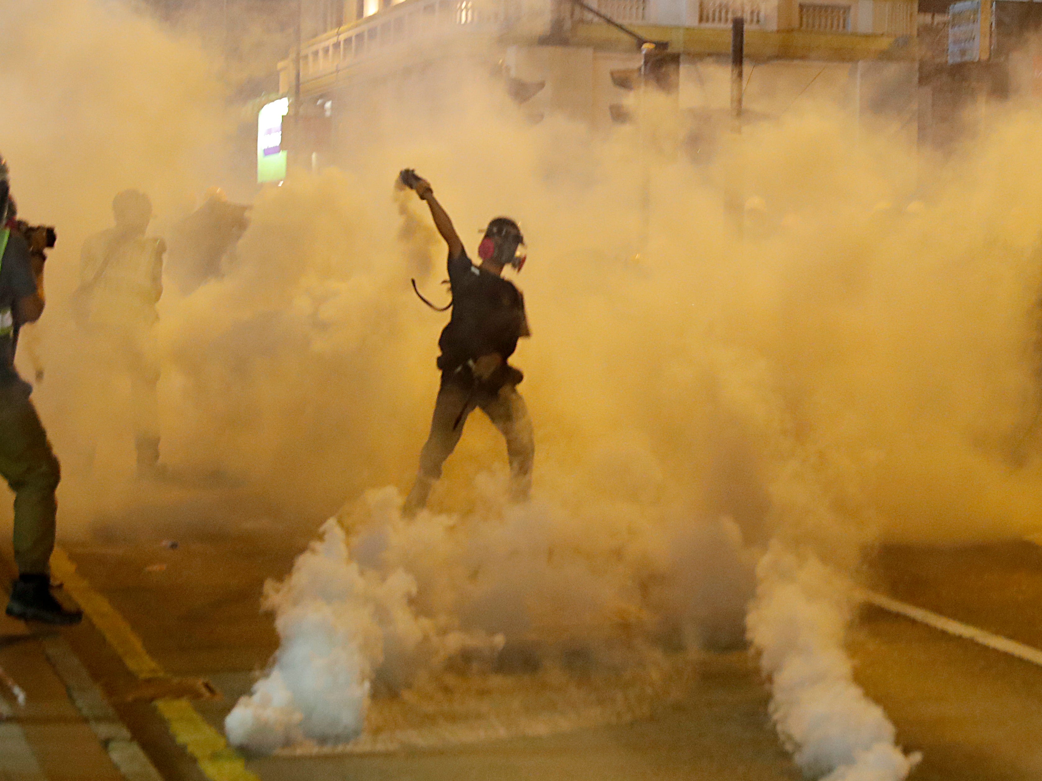 A protester throws back a tear gas canister during a confrontation with police in Hong Kong on Saturday, Aug. 3, 2019. Hong Kong protesters removed a Chinese national flag from its pole and flung it into the city's iconic Victoria Harbour on Saturday, and police later fired tear gas at demonstrators after some of them vandalized a police station. 