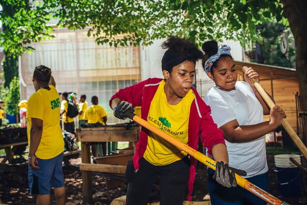 A counselor, Yesenia Leon, center, and Ta’Cora Glenn, a camper, turning compost as they dance to the music of Michael Jackson and others at Harlem Grown’s 127th Street farm.