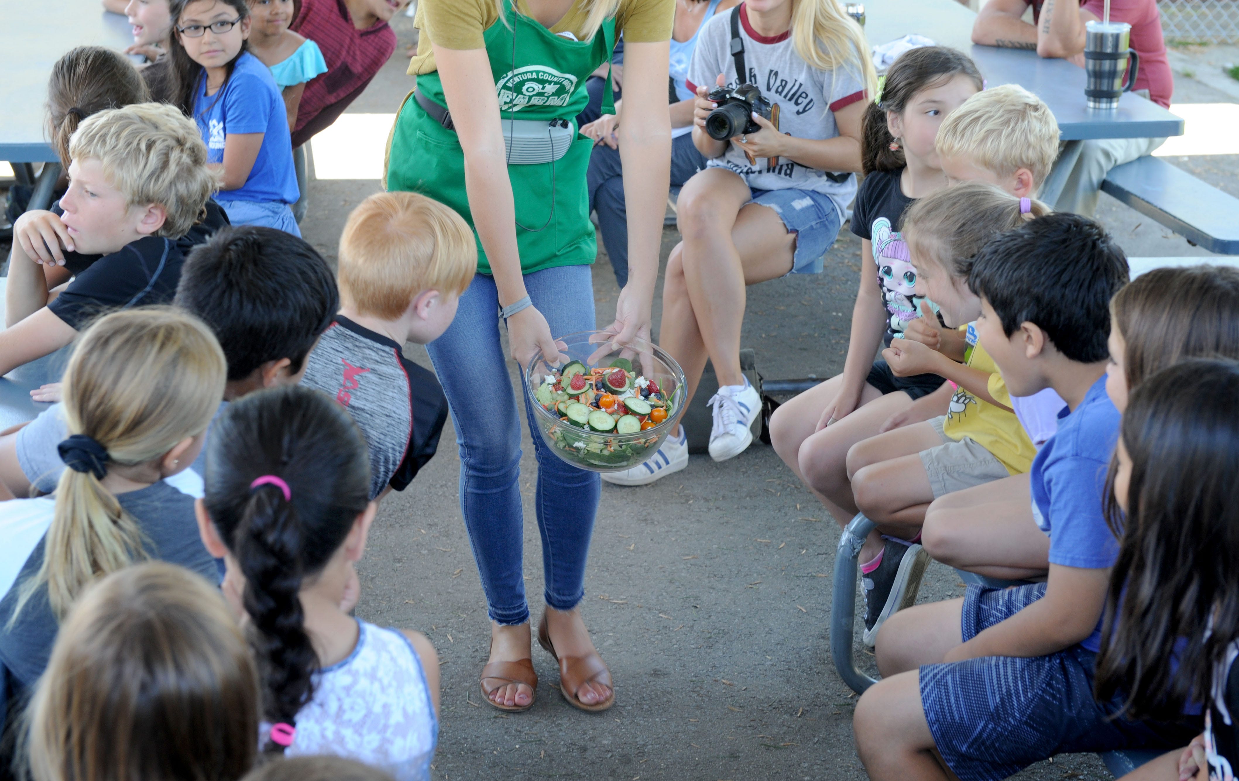 Emily Skaar, nutritional program coordinator for Students for Eco-Education and Agriculture, shows a salad to a group of third-graders as the nonprofit's 30-foot Farm Fresh van came to Mound Elementary in Ventura.