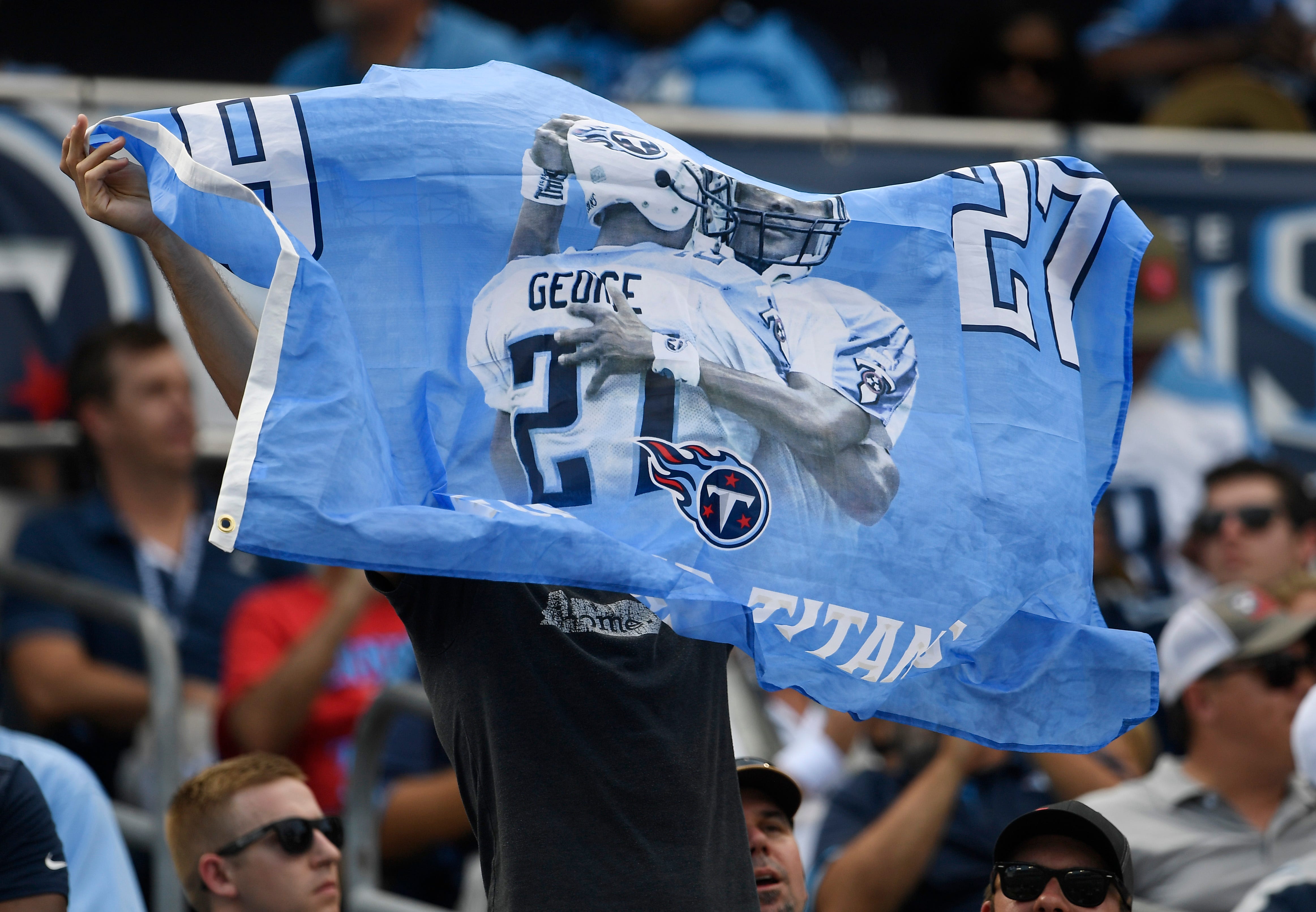 A Tennessee Titans fan holds a banner in support of Eddie George and Steve McNair whose jersey numbers were retired at halftime at Nissan Stadium Sunday, Sept. 15, 2019 in Nashville, Tenn. 