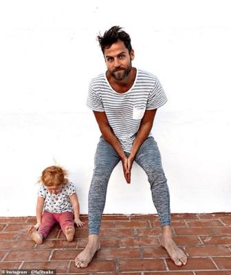 a man standing next to a brick wall: Workout out with his children: The fitness and his daughter do some fitness moves together in this Instagram snap