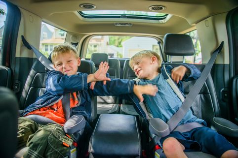 Twin brothers sitting in back of vehicle, fighting