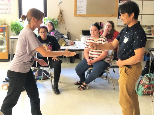 South-Doyle Middle School teacher Jennifer Sauer and Japanese Club guest Shigetoshi Eda demonstrate a Japanese game for the students.