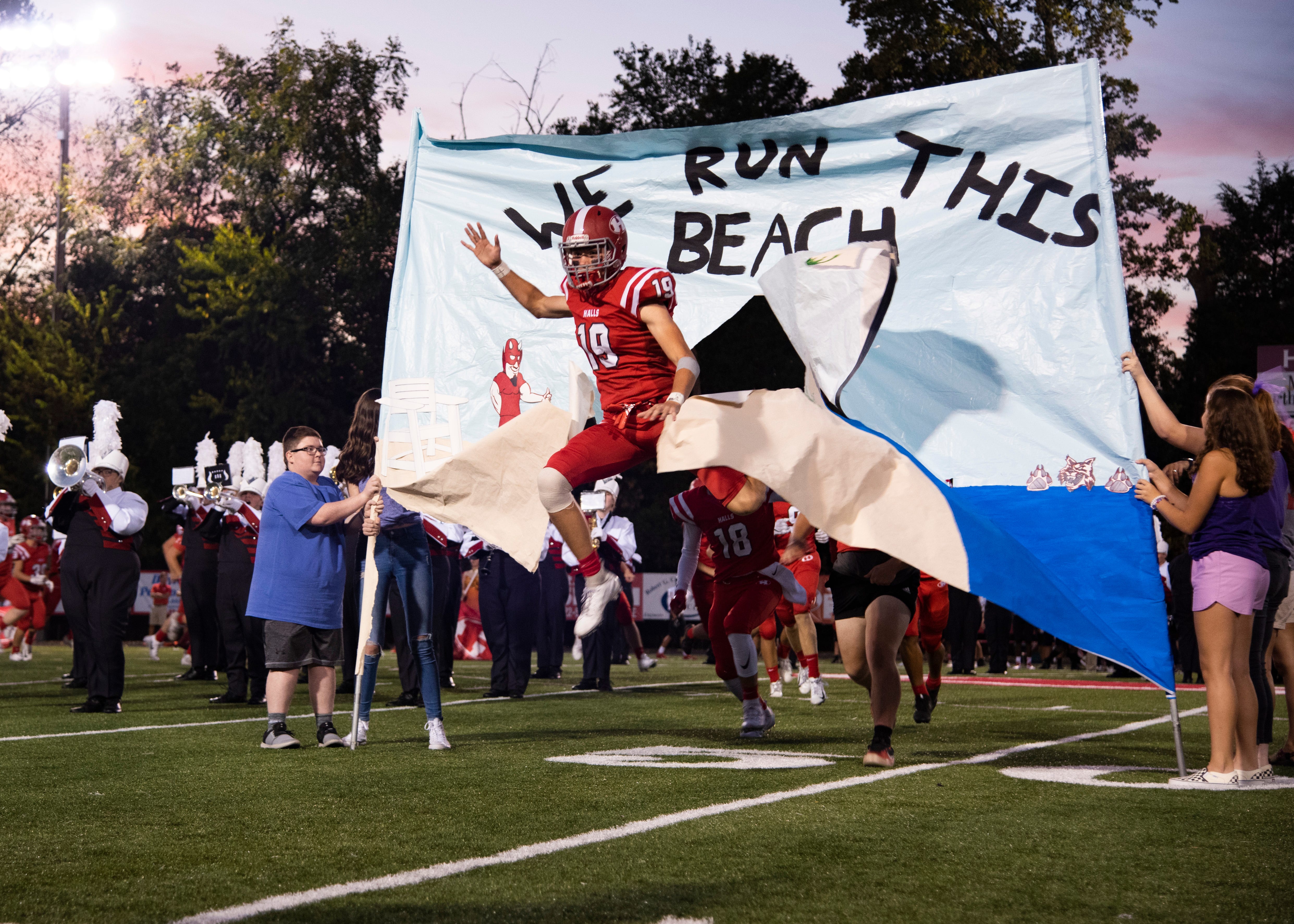 Halls' Brayden Beal (19) jumps through a spirit banner before the Halls and Central high school football game on Friday, October 4, 2019 at Halls High School.
