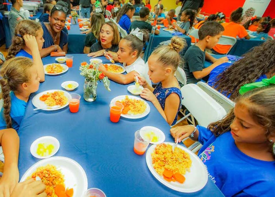Anucha Brown, Chief Engagement, Advocacy and Global Programs Officer at UNICEF USA (top left) and Olga Ramos, President of the Boys & Girls Clubs of Puerto Rico, talk with kids enjoying a healthy dinner at the Las Margaritas Club. 