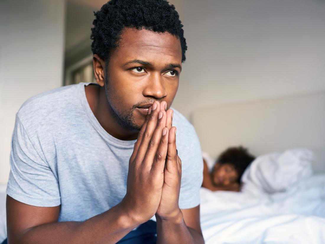 a man feeling regret at the end of the bed. 