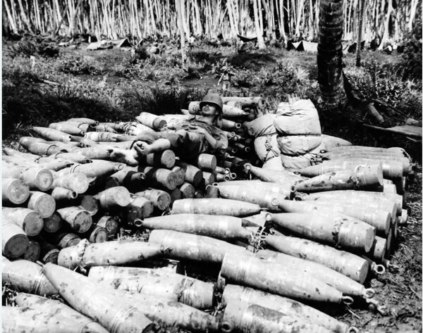 Catching 40 winks between his duties of supplying a 155 mm gun with shells, this barefooted serviceman finds himself a bed top his ammunition dump on Rendova on 30 June 1943. (National Archives)