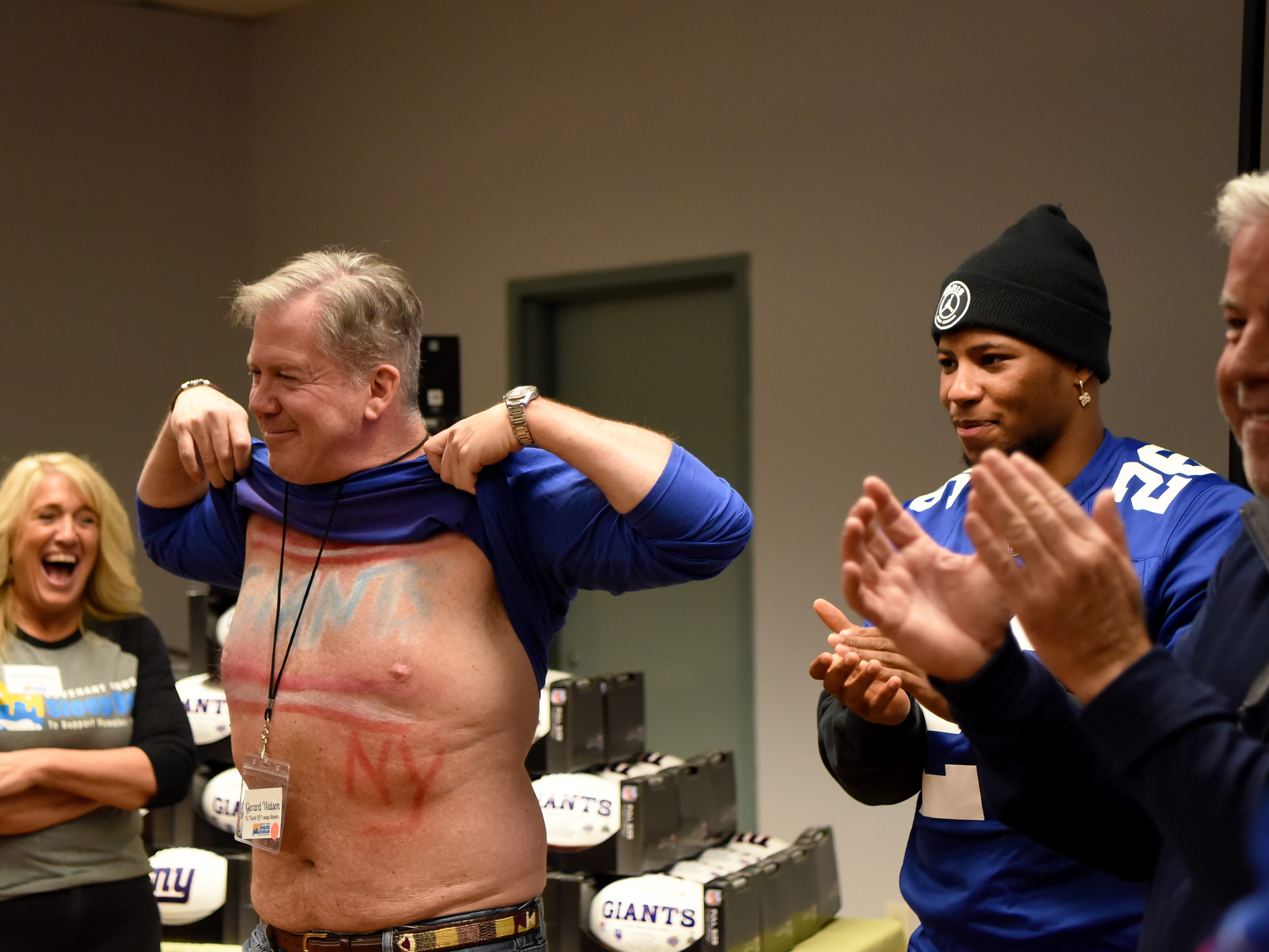 Covenant House holds a Sleep Out Executive Edition in Newark on Thursday November 21, 2019. (From left) Janette Scrozzo laughs, Gerard Watson lifts his shirt as Saquon Barkley and Jim White applaud. 