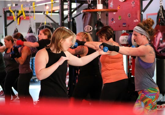 Leah Traciak-Zenker, left, co-owner of EmPOWer gym instructs students during a long warm-up session on Saturday, Nov. 23, 2019.