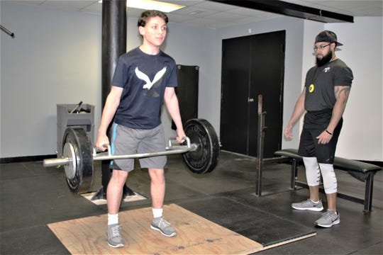 Taylor Gundy, right, a trainer at Phase 6 Strength and Performance in Marion, guides Nygil Horn, left, a club hockey player who is a sophomore at River Valley High School, through his daily workout. Horn plays for the Northeast Storm of the Ohio Scholastic Hockey League.