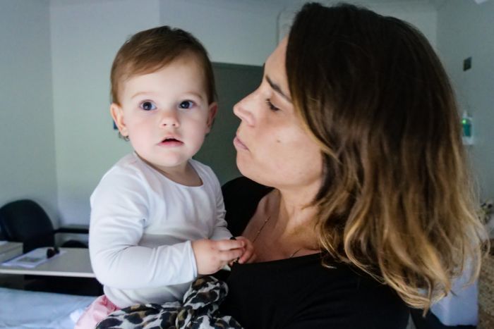 A woman holds her 12 month old daughter